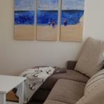 Wohnzimmer mit Sofa, Tisch und Wandbildern