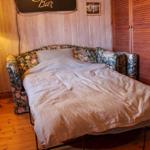 Schlafzimmer mit Bett, Lampe und Holzwand.