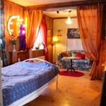 Schlafzimmer mit Bett, Spiegel und Sofa im Hintergrund.