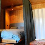Schlafzimmer mit Bett, Vorhängen und Holzwand