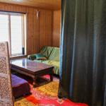 Ein Raum mit Holzwand, Sofa, Tisch und Vorhang.