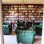 Ein Raum mit grünen Sesseln und einer Bücherwand.