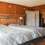 Doppelbett in einem Zimmer mit Holzwandverkleidung und Spiegelschrank.