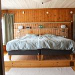 Schlafzimmer mit Holzwand, Bett und Fenster