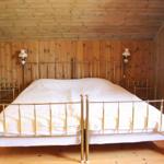 Schlafzimmer mit Holzwand und goldfarbenem Bettgestell.