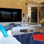Wohnzimmer mit Sofa, TV, Tischen und Holzwand