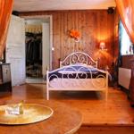 Schlafzimmer mit Holzwand, Metallbett und orangefarbenen Vorhängen.
