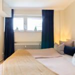 Schlafzimmer mit Bett, Fenster und Vorhängen