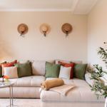 Ein Wohnzimmer mit Sofa, Kissen und Pflanzen an den Wänden.