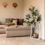 Wohnzimmer mit Sofa, Kissen und Zimmerpflanze in einem weißen Käfig.