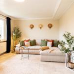 Wohnzimmer mit Sofa, Fernseher und Pflanzen.