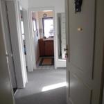 Flur mit Tür und Blick in Küche mit Holzschrank und Fenster