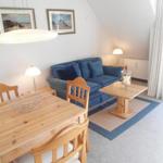 Wohn- und Essbereich mit Holztisch, Sofa und Fenster.