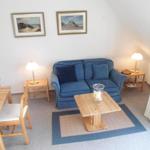 Wohn- und Essbereich mit blauem Sofa, Holztisch und Bildern an der Wand.