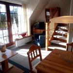 Wohn- und Essbereich mit Holztreppe und großem Fenster. Möbel und Einrichtung sind sichtbar.