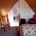 Schlafzimmer mit Dachschrägen, Bett, Stuhl und Sessel.