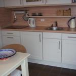 Küche mit Arbeitsplatte, Spüle, Kaffeemaschine und Tisch mit Schale.