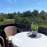 Terrasse mit Tisch, Stühlen und Lavendel. Blick auf grüne Hügel und Häuser.