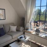 Wohnzimmer mit Sofa, Tisch und Blick auf Balkon mit Garten.