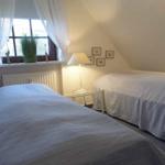 Zwei Betten unter einem Dachbodenfenster mit Vorhängen und einer Stehlampe.