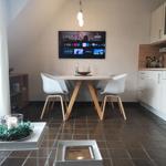 Essbereich mit Tisch, Stühlen und Fernseher an der Wand.