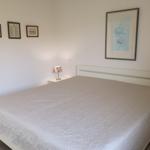 Schlafzimmer mit Bett, Nachttisch und Wandbildern.