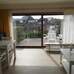 Wohnraum mit Blick auf Terrasse und Garten. Weiße Möbel und große Fenster.