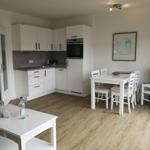 Wohnküche mit Esstisch, TV und Küchenzeile.