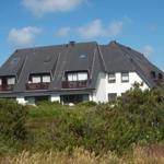 Ein zweistöckiges Haus mit Balkon und Dachfenstern, umgeben von Grünflächen.