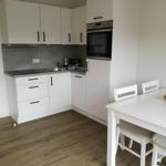 Küche mit weißer Einbauküche, Edelstahlherd und Esstisch mit Stühlen.