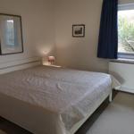 Schlafzimmer mit Bett, Fenster und Wandbildern.