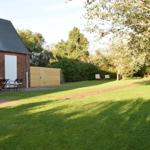 Haus mit Garten, Terrasse und Sitzgelegenheiten unter Bäumen.