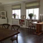 Eingangsbereich mit Tisch, Stühlen und Bücherregal unter Fenstern.