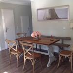 Essbereich mit Holztisch, Stühlen und Bänken. Wandbild zeigt Segelyacht.