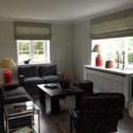 Wohnzimmer mit Sofa, Sessel, Couchtisch und Fenstern.