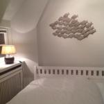 Schlafzimmer mit Bett, Wanddekoration und Nachttisch mit Lampe.