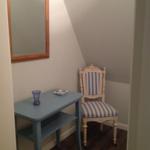 Ein kleiner Schreibtisch mit Stuhl und Spiegel an der Wand.