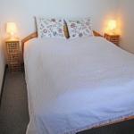 Schlafzimmer mit Bett, zwei Nachttischen und Lampen.