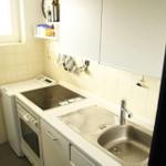 Küche mit Herd, Spüle und weißen Schränken