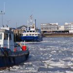 Hafen mit Eis und Schiffen. Blick auf moderne Gebäude im Hintergrund.