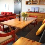 Essbereich mit Holztisch, roten Stühlen und Sofa mit Kissen.