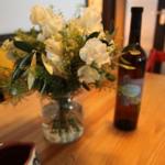 Auf dem Tisch steht eine Blumenvase und eine Weinflasche.
