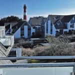 Blick von Balkon auf Leuchtturm und moderne Häuser.