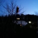 Roter Leuchtturm mit beleuchteter Laterne bei Dämmerung