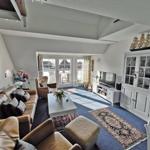 Wohnzimmer mit Sofa, Fernseher und Balkonzugang.