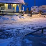 Schneebedeckter Außenbereich mit Haus und Eisfläche bei Nacht.