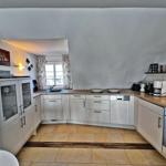 Küche mit weißen Schränken, Holz Arbeitsplatten und Fenster mit Vorhängen.