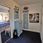 Flur mit Kleiderschrank, Wandbild und Blick in Schlafzimmer mit Bett.