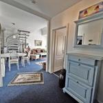 Eingangsbereich mit blauem Teppich und Spiegelschrank. Blick in Wohn- und Essbereich mit Treppe.