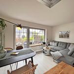 Wohn- und Essbereich mit Sofa, Tisch und Fenster zur Terrasse.